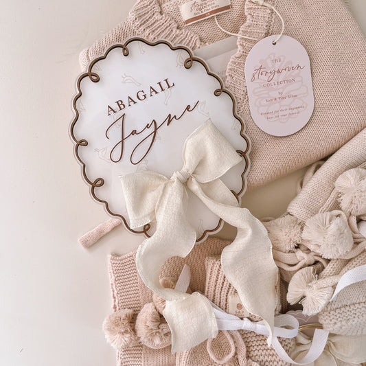 Personalised acrylic baby name plaque with bow featuring Abigail Jayne styled with newborn outfit