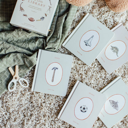 Children's books with illustrations on a textured surface with a teddy bear and green fabric.