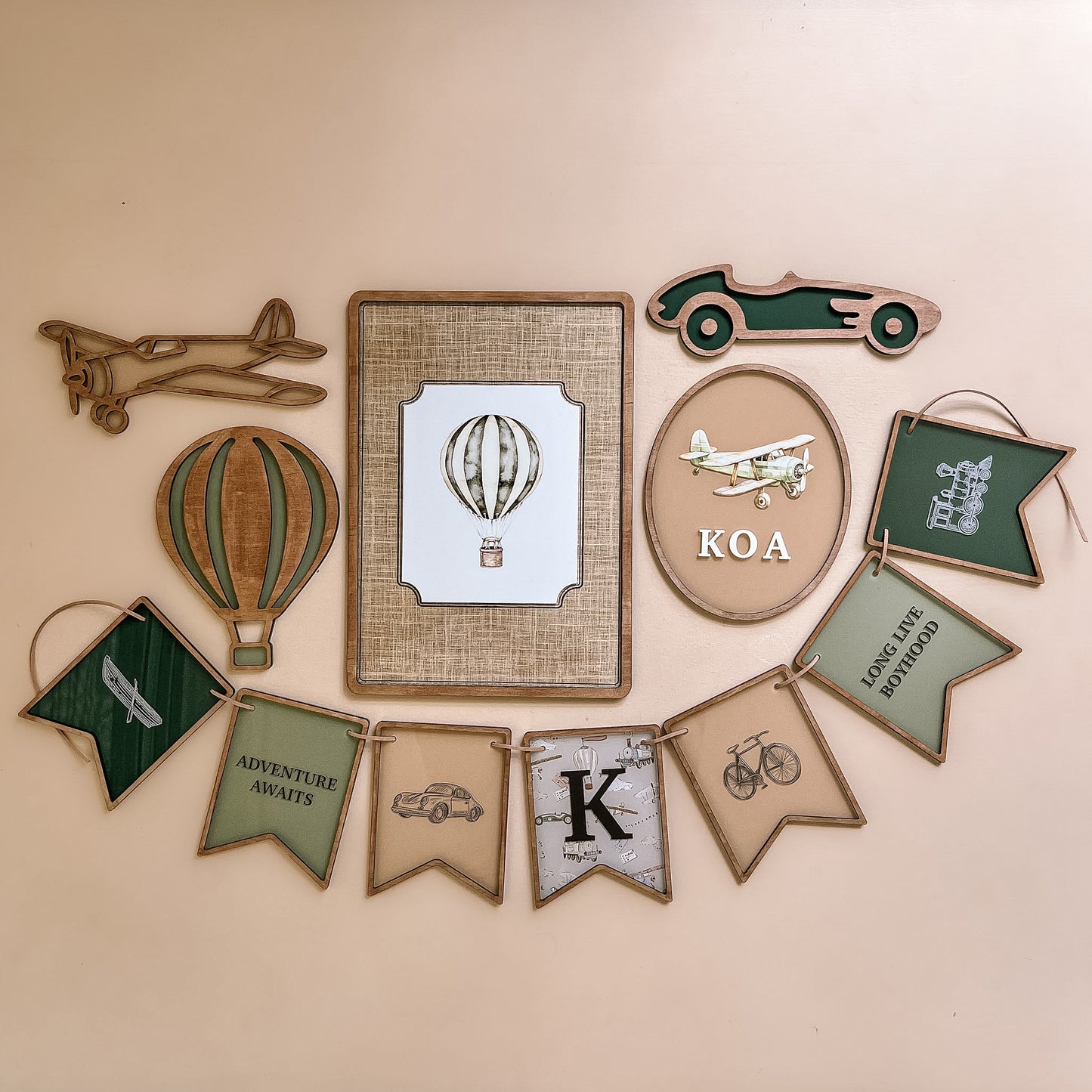 Vintage style nursery wall decor featuring aeroplane hot air balloon framed print and personalised name banner in neutral tones
