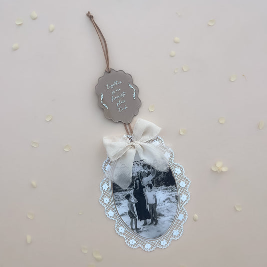 Oval photo keepsake with lace edge frame ribbon bow and family photo on neutral background
