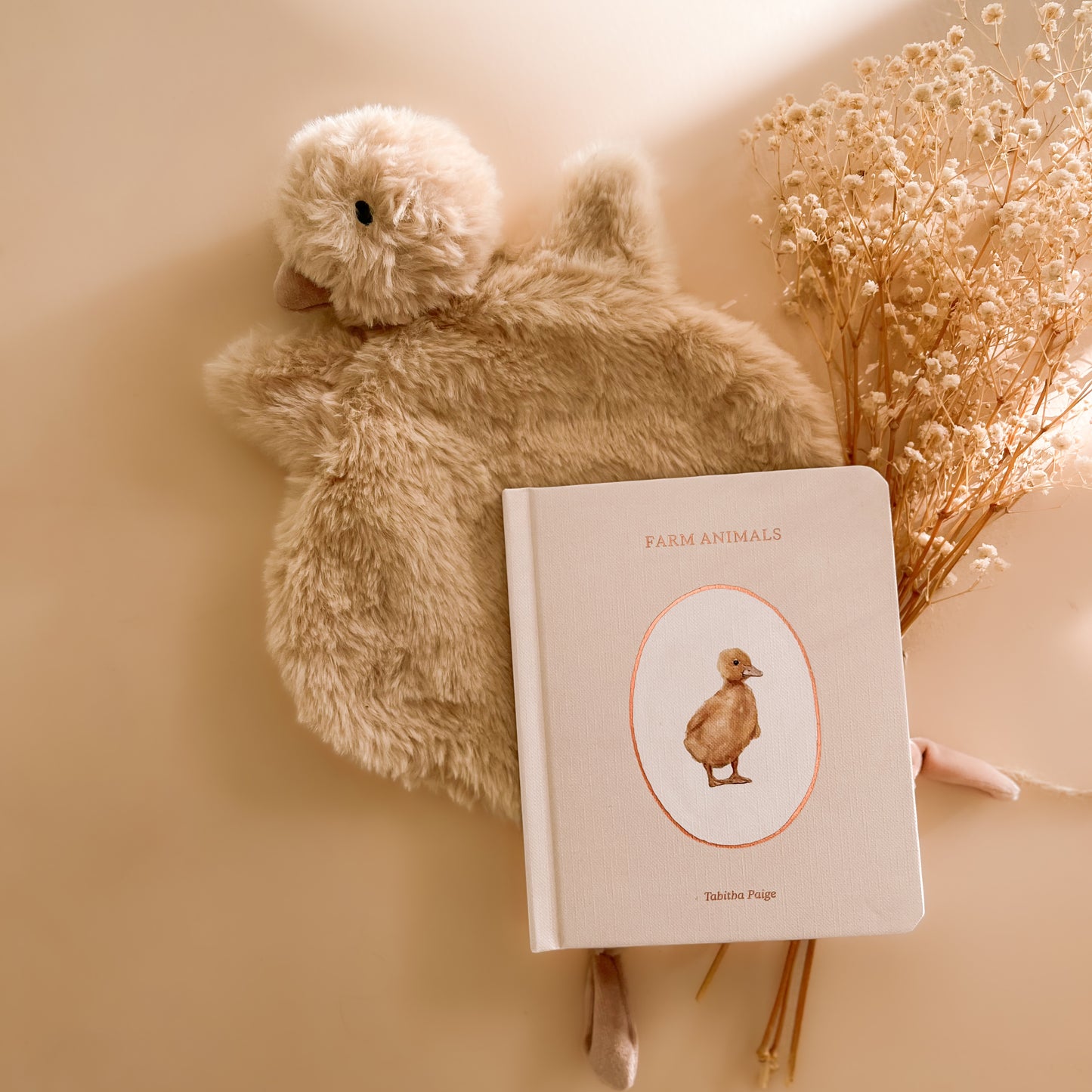 Soft duck baby comforter styled with neutral farm animal baby book and nursery décor