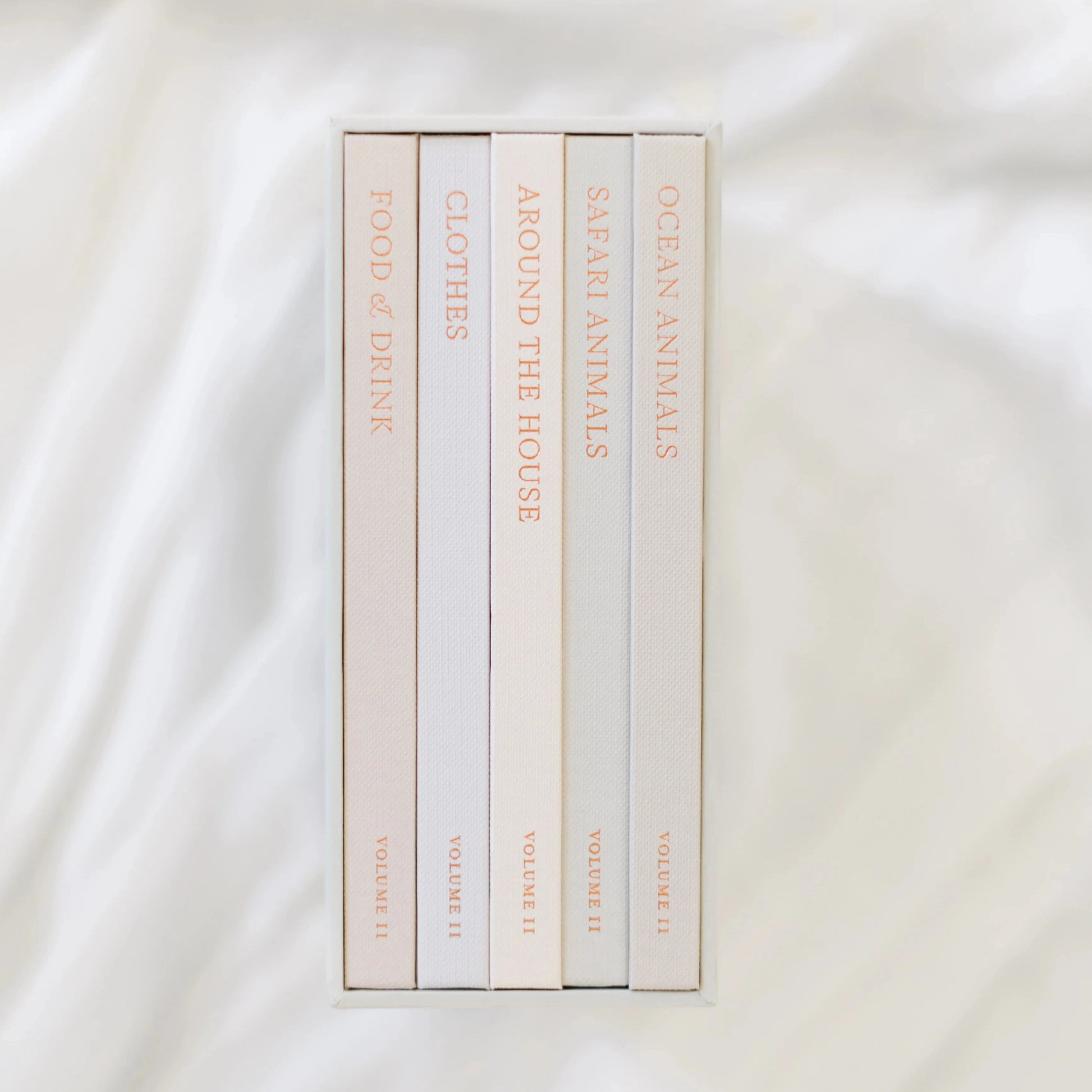 Set of books with gold text on a white fabric background